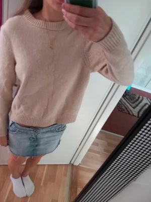 Beige stickad tröja från Filippa K - Mysig beige stickad tröja från Filippa K med rund halsringning och ribbade muddar vid ärmslut och nederkant. Enkel och stilren design som passar perfekt till många olika outfits. Tillverkad i mjukt material för extra komfort. Kortare och mindre modell. Ull och Kashmir. Inga tecken för användning 
