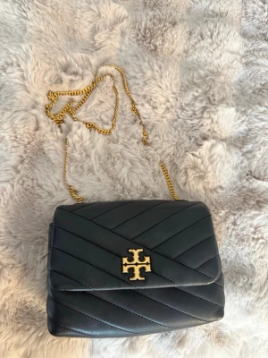 Svart quiltad handväska Tory Burch - Snygg svart quiltad handväska från Tory Burch i läder med guldfärgad kedjerem. Köpt på second hand men helt ny. Använd en del men är fortfarande i bra skick!💕
