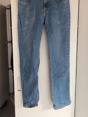 Ljusblå raka lee jeans - Säljer ett par klassiska ljusblå lee jeans med rak passform och fem fickor. Jeansen har normal midja och subtila slitningar för en avslappnad look. Perfekta till vardagsstilen och tillverkade i bomullsdenim.