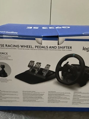 Logitech G923 SE ratt, pedaler & växelspak - Säljer ett Logitech G923 SE racingset med ratt, pedaler och växelspak. Ratten är svart med blå detalj, har flera knappar och är klädd i slitstarkt material. Pedalerna är i metall och plast, designade för realistisk racingkänsla. Perfekt för PlayStation och PC. (Priset kan diskuteras)