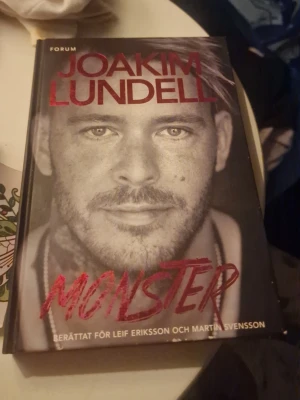 Monster av Joakim Lundell - En gripande självbiografisk bok av Joakim Lundell, berättad för Leif Eriksson och Martin Svensson. Omslaget är svartvitt med röd text och ett porträttfoto. Inbunden bok, perfekt för dig som gillar starka livsberättelser och modern svensk skönlitteratur.