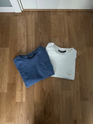 J.Lindeberg - Säljer två stilrena t-shirts från J.Lindeberg, en i ljusblått och en i vitt. Båda har rund halsringning och en diskret patch på bröstet. Perfekta basplagg i mjuk bomull som passar till det mesta.