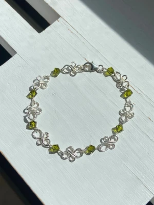 Handgjort 925 silver armband med mossgröna pärlor  - Handgjort armband av mig gjort av 925 silver tråd. Pärlorna är 4 mm mossgröna Tjeckiska MC bicone pärlor. Formerna är lödda på baksidan som ni kan se på den sista bilden för hållbarhet och design. Längd på armband: ca 16 cm Tråd tjocklek på formerna: 0,8 mm Tråd tjocklek där pärlan sitter: 0,6 mm Kolla gärna in mina andra annonser då jag ofta säljer liknande armband och smycken