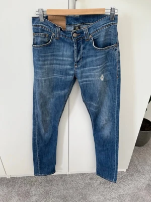 Blå jeans från Dondup Lucky, stl 31 - Snygga blå jeans från Dondup, modell Lucky, i klassisk femficksdesign. Jeansen har en lätt tvättad look med diskreta slitningar och raka ben. Perfekta för dig som gillar en avslappnad men stilren stil.