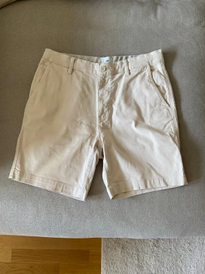 Beige shorts från H&M i bomull - Snygga beige shorts från H&M med klassisk passform. Tillverkade i mjuk bomull med två sidofickor fram och två passpoalfickor bak. 