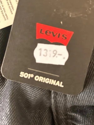 Levi's 501 Original svarta jeans W24 L28 - Klassiska svarta Levi's 501 Original jeans med rak passform och fem fickor. Ikonisk röd Levi's-tag på bakfickan och läderpatch i midjan. Tillverkade i slitstark denim, perfekt för en tidlös look.