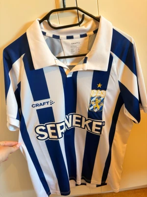 IFK Göteborg matchtröja blåvit - Säljer en IFK Göteborg matchtröja från Craft med klassiska blå och vita vertikala ränder. Tröjan har klubbmärke, sponsorlogga och krage. Perfekt för dig som vill visa ditt stöd på läktaren eller på planen. Som ny, använd 2 gånger. Säljes då den är lite stor på mig.