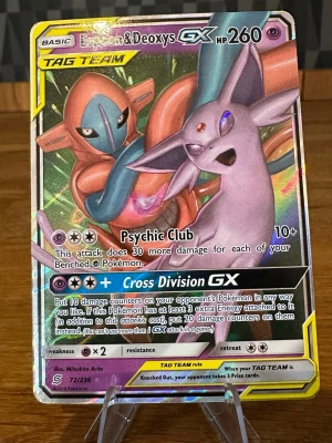 Pokémonkort Espeon & Deoxys GX - Säljer ett holografiskt Pokémonkort med Espeon & Deoxys GX från TAG TEAM-serien. Kortet har färger i lila, blått och orange med metallic-effekt och är på engelska. Perfekt för samlare eller Pokémon TCG-spelare som vill ha en unik och kraftfull duo i sitt deck.