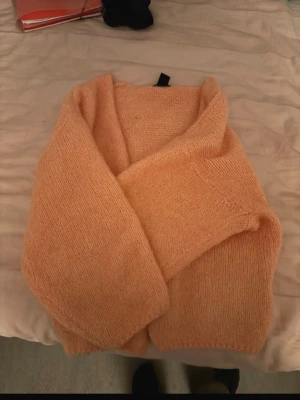 Persikofärgad stickad tröja - Mysig stickad tröja i persikofärg med bred krage och lång ärm. Tröjan är gjord i ett mjukt, fluffigt material som ger en avslappnad och trendig look. Perfekt för dig som gillar en enkel men snygg stil.storlke den är aprikos