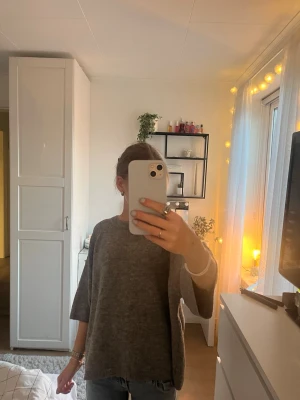 Grå stickad tröja med halvlånga ärmar - Mysig grå stickad tröja med bred ribbad halsringning och halvlånga ärmar. Tröjan är over size och är tillverkad i mjukt material . Enkel och stilren design som passar till det mesta.