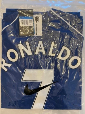 Ronaldo fotbollströja 2008 - Helt ny! Säljer en blå fotbollströja från Nike med Ronaldo och nummer 7 tryckt på ryggen. Tröjan har vita detaljer och är tillverkad i ett lätt, andningsbart material som passar perfekt för träning eller match. Klassisk sportig design med tydligt Nike-logga.