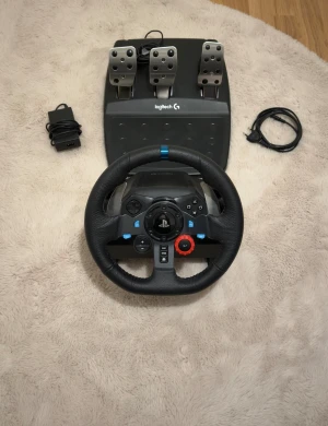 Logitech G29 Driving Force Racing Wheel - Logitech G29 ratt och pedaler för racing-spel. Kompatibel med PlayStation och PC. Komplett med strömadapter och kablar. Mycket fint skick, inga synliga repor eller slitage. Perfekt för realistisk racingupplevelse hemma.