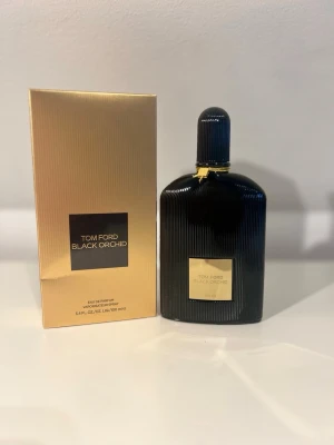 Tom Ford Black Orchid EdP 100 ml - Lyxig parfym från Tom Ford i modellen Black Orchid. Flaskan är svart med räfflad yta och har en elegant guldfärgad etikett och detaljer. Kommer i en snygg guldfärgad kartong. Innehåller 100 ml Eau de Parfum.
