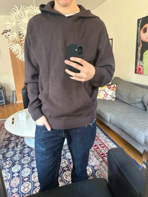 Stickad hoodie  - Mörkbrun stickad hoodie med klassisk passform och känguruficka framtill. Nypris 699