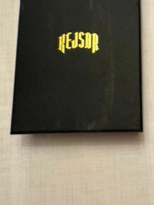 Svart låda med Kejsar-logga - Säljer en stilren svart låda med Kejsar-logga i guld på locket. Lådan är rektangulär och gjord av hård kartong, perfekt för förvaring eller som presentask. Logotypen är tryckt i en cool, modern font.