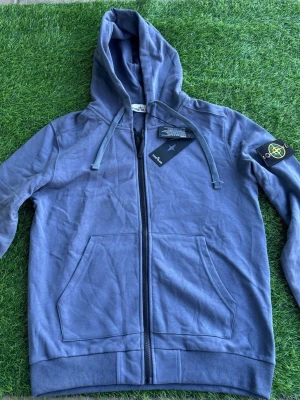 Stone Island Hoodie Zip Patch – Navy / Blå - Säljer en zip-hoodie från Stone Island i snygg blå/grå färg. Väldigt clean modell med den klassiska patchen på armen.    Bra skick och skön kvalitet. Perfekt till både vardag och streetwear fits.    Storlek: M Skick: Bra skick   Nypris: ca 3500+    Skickas eller möts upp. Hör av dig vid frågor!