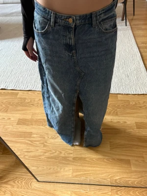 Lång jeanskjol från Zara med slits - Säljer en snygg lång jeanskjol från Zara i klassisk blå denim. 