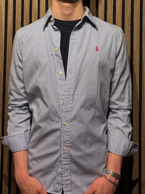 Randig skjorta från Ralph Lauren - Klassisk skjorta från Ralph Lauren med smala blå och vita ränder.  Storlek 10/S