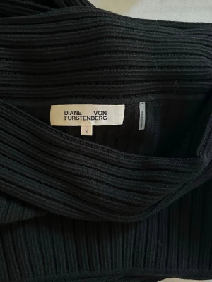 Svart ribbad offshoulder topp DVF - Svart ribbad off-shoulder topp från Diane von Furstenberg med smickrande passform och elegant design.   En stilren designer-topp som passar perfekt både till jeans, kjol eller kostymbyxor och funkar lika bra till middag som fest.  Storlek S. Mycket fint skick. Nypris ca 3000kr.  