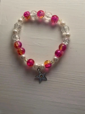 Färgglatt pärlarmband med stjärnberlock - Säljer ett handgjort armband av mig med pärlor i rosa, orange, vitt och transparent. Armbandet har en söt stjärnberlock i metall. 18cm omkrets❤️