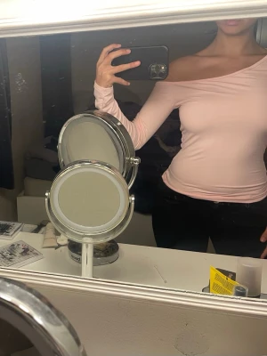 Ljusrosa oneshoulder topp - Säljer en ljusrosa oneshoulder topp med lång ärm. Toppens passform är tight och den har en snygg offshoulder-design som ger en cool look. Perfekt att matcha med jeans eller kjol för en trendig outfit.