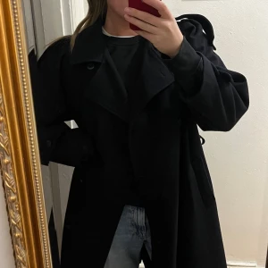 Marinblå kappa i ull - En marinblå kappa i ull. Dubbelknäppe , kommer med ett skärp som man kan knyta i midjan. Fina detaljer. 