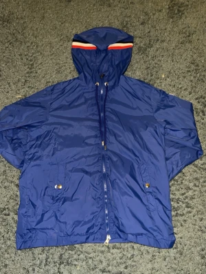 Moncler Vind Jacka - Moncler jacka, perfekt nu inför våren. Den är tydligt blå med röd, vita detaljer runt huvan, och fint detaljerade Moncler silver knappar. Säljer den då den har blivit för liten för mig. Den är i Moncler storlek 2, vilket är ungefär S/M. Passar defenutivt S iallafall.  Inte använd mer än 10 gånger. Ge gärna prisförslag och dm om mer information! :)