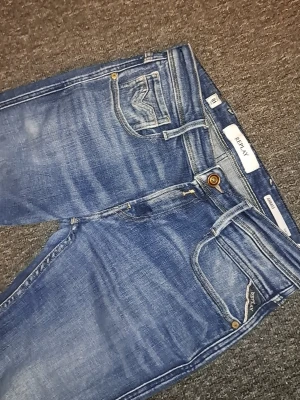 Blå jeans från Replay - Snygga blå jeans från Replay med klassisk femficksdesign och coola slitningar. Jeansen har en normal passform och detaljer som kontrastsömmar och läderpatch bak. Materialet är denim med en skön känsla och tvättad look. Nästan helt nya. L30 W 29 Kan diskutera pris. Passar dig som är runt 160-170
