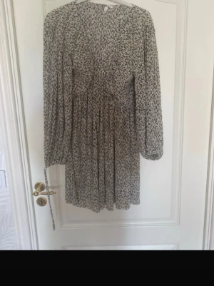 Blommig kortklänning - Supersöt populär klänning från H&M. Den är v-ringad med puffiga ärmar och knytning. Perfekt nu till sommaren.  Använd fåtal gånger