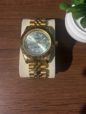 Klocka - Snygg klocka med klassisk länk och räfflad bezel. Urtavlan är ljus med tydliga index och datumvisning. Perfekt accessoar för dig som vill sticka ut med stilren och lyxig design. Priset kan diskuteras!