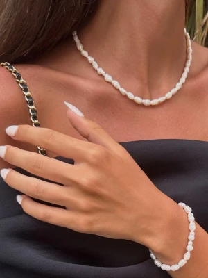 Äkta sötvattenspärl halsband - Stilrent halsband med oregelbundna vita äkta sötvattenspärlor och små guldfärgade detaljer. Halsbandet har ett justerbart lås med kedja och en liten rund bricka som är i rostfritt stål. Köpt i Italien på Sardinen