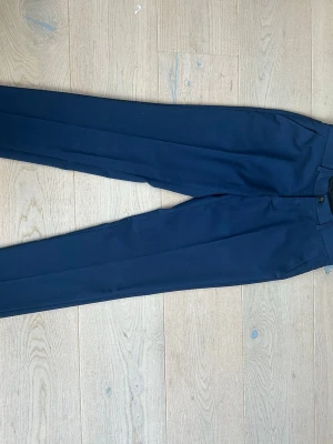 Mörkblå kostymbyxor, rak modell - Snygga mörkblå slim kostymbyxor med rak passform och pressveck. Materialet känns lätt och slätt(77%polyester)
