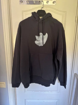 Adidas skateboarding shmmfoil hoodie med spöke på bröstet - Cool svart hoodie med en vit spök-illustration på bröstet. Hoodien har huva med dragsko och en stor magficka framtill. Tillverkad i mjukt material och har ribbade muddar vid ärmar och nederkant. Perfekt för dig som gillar streetwear och unika tryck.