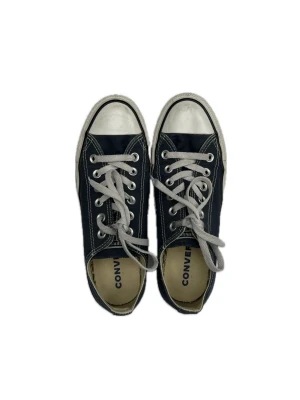 Mörkblå Converse låga sneakers - Klassiska mörkblå Converse sneakers med vita gummisulor och tåhätta. Skorna har vita snören och silverfärgade öljetter. Låg modell. Storlek 39. Äkta converse som är sparsamt använda, de enda som tyder på att de har använts är att de vita delarna är lite färgade av smuts. Sista bilden visar färgen bäst.