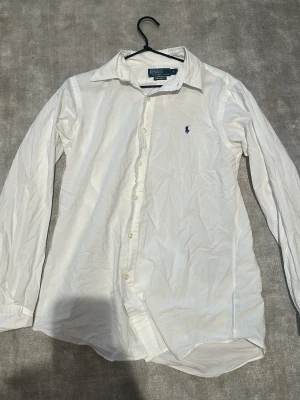 Vit polo ralph lauren skjorta - En vit polo ralph lauren skjorta i bra skick förutom ett litet hål bakom kragen men syns ej vid användning hör av er vid frågor 