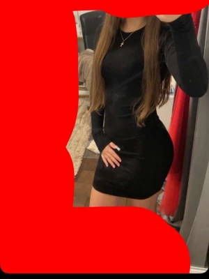 Svart tight långärmad klänning - Snygg svart bodycon klänning med lång ärm och rund halsringning. Klänningen är kort och har en stilren, enkel design som framhäver figuren. Perfekt för dig som gillar en minimalistisk look.