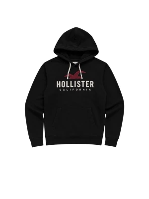 Svart Hollister hoodie med logga - Svart hoodie från Hollister med stor vit broderad logga och röd fågel på bröstet. Klassisk känguruficka framtill och vita dragsnören i huvan. Tillverkad i mjuk bomullsblandning för extra komfort. Perfekt för en avslappnad och trendig look.