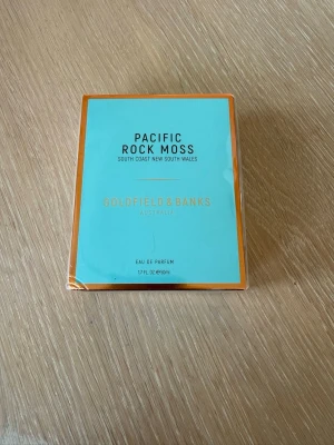 Goldfield & Banks Pacific Rock Moss EdP - Parfymen Pacific Rock Moss från Goldfield & Banks kommer i en snygg turkos och guldig kartong. Doften är inspirerad av Australiens kust och är en Eau de Parfum på 50 ml. Oöppnad.