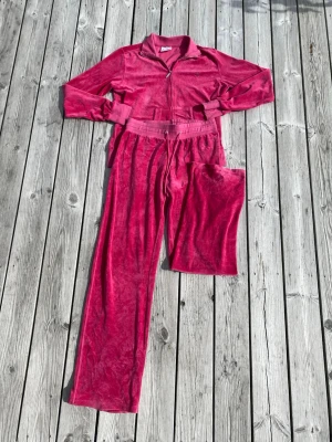 Y2K juicy couture liknande velour set från Champion - Säljer detta Y2K velour set från champion eftersom de inte kommer till användning längre. Byxorna har lite av en baggy look, benen är raka och har en liten utsvängning längst ner. Dem är mid-low waisted beroende på om man viker ner byxorna. Båda plaggen är i exemplariskt skick då det inte finns några tecken på användning och alla stenar på loggorna finns kvar. INNERBENSLÄNGD: 79cm OBS: Det står att de är i storlek L men eftersom de är vintage och storlekarna var mindre förr så passar de främst d