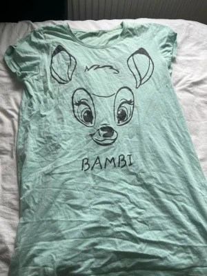 Mintgrönt nattlinne med Bambi-tryck - Superfint mintgrönt nattlinne med stort Bambi-tryck framtill. Mjuk och skön bomullskänsla, rund halsringning och korta ärmar. Perfekt för mysiga hemmakvällar eller när du vill sova extra bekvämt.