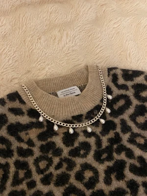 Silverfärgat halsband med pärldroppar - Snyggt halsband i silverfärgad rostfritt med kedja och hängande droppformade pärlor. Perfekt för att ge din outfit en trendig och elegant touch. Passar till många olika stilar och är lätt att matcha med andra accessoarer.