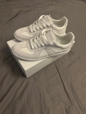 Vita maison margiela skor - Stilrena maison margiela skor ovandel i både mocka och slätt läder. Klassisk låg modell med vita skosnören och diskreta detaljer. Perfekta för dig som gillar minimalistisk och clean stil. Använda 1 gång och har kvar orderbekräftelse från köpet