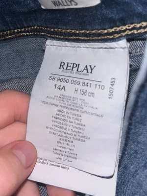 Blå jeans från Replay - Säljer ett par klassiska blå jeans från Replay med snygga kontrastsömmar och knappgylf. Jeansen har normal midja och bälteshällor, perfekta till en avslappnad stil. Materialet är slitstarkt denim som håller länge.