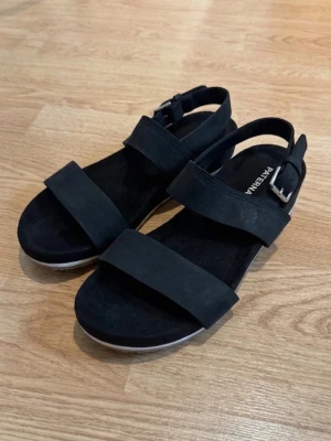 Svarta sandaler från Timberland - Svarta sandaler från Timberland med två breda remmar över foten och justerbart spänne vid ankeln. Använda ett par gången, men fortfarande i bra skick💕 nypris: 1000 kr 