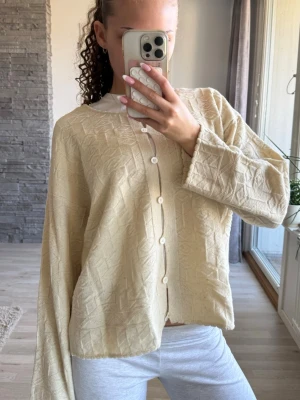 Beige mönstrad kofta med knappar - Säljer en beige kofta med diskret geometriskt mönster och vita knappar framtill. Använd fåtal gånger, sitter som en s💕