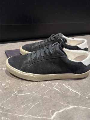 Svarta Saint Laurent skor - Snygga svarta sneakers i mocka. Perfekta för dig som gillar stilrena skor. Priset kan diskuteras.