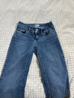 Blå bootcut jeans med broderade fickor - Säljer ett par blå bootcut jeans med snygga broderade detaljer på bakfickorna. Jeansen har klassisk femficksmodell, normal midja och stängs med dragkedja och knapp. Perfekta till en avslappnad stil och passar till det mesta.