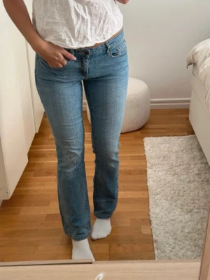  ljusblå bootcut jeans - Säljer ett par ljusblå bootcut jeans med låg midja. Jeansen har en avslappnad passform och är tillverkade i mjuk denim med lätt stretch. Jättefin färg som passar bra inför sommaren.