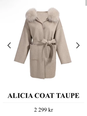 Kappa - Stilren taupefärgad rock med äkta päls på kragen och knytskärp i midjan. Rocken har två stora framfickor och en rak, avslappnad passform. Perfekt för dig som vill ha en trendig och mysig look. Stolek M