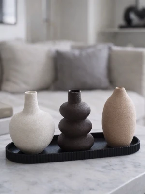 Set med tre dekorativa vaser - Säljer ett set med tre små dekorativa vaser i olika former och färger: en beige, en brun med vågig form och en sandfärgad. Alla är tillverkade i plast med en matt, strukturerad yta. Perfekta som inredningsdetaljer på soffbord eller hylla.